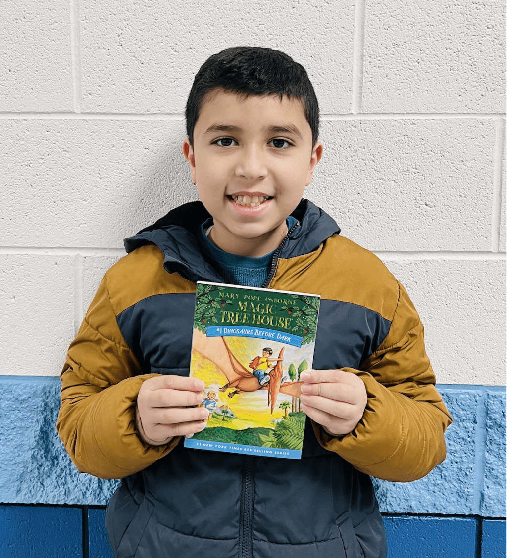 student holding a book received for earning a  praise award